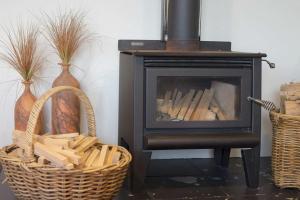 a fireplace with two baskets and two vases at Chester Cottage Beachfront - direct ocean access in Oakura