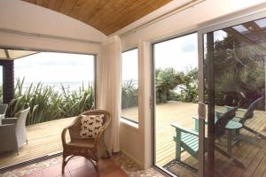 a screened in porch with a view of the ocean at Chester Cottage Beachfront - direct ocean access in Oakura