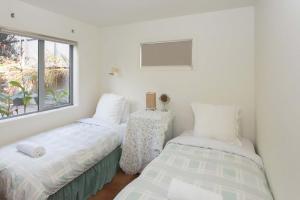two beds in a room with a window at Chester Cottage Beachfront - direct ocean access in Oakura +16 photos