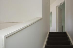 a staircase in a house with white walls and black stairs at Chester Cottage Beachfront - direct ocean access in Oakura