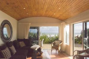 a living room with a couch and a view of the ocean at Chester Cottage Beachfront - direct ocean access in Oakura