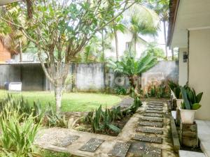 a garden with a walkway in a yard at The SO Hotel Mitra RedDoorz in Pangandaran