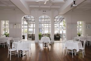 a room with white tables and chairs and windows at Ambassadors Hotel in Adelaide