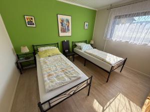 two beds in a room with a green wall at Ferienwohnungen Stollhof in Mehring