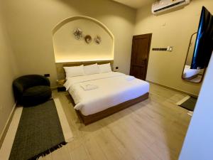 a bedroom with a large white bed and a chair at Betham Chalet in Nizwa +29 photos
