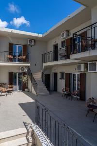 a building with a balcony with tables and chairs at Cactus in Skiathos