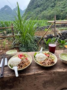 two plates of food on a wooden table with rice at Nùng Indigo in Cao Bằng