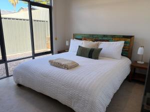 a bedroom with a white bed with a large window at The Mandurah Hideaway in Mandurah