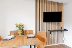 a dining room with a table and a television on a wall at Apartment am Bischofsberg in Großheubach