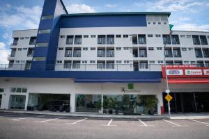 a white and blue building with a parking lot at Thy Executive Hotel in Johor Bahru