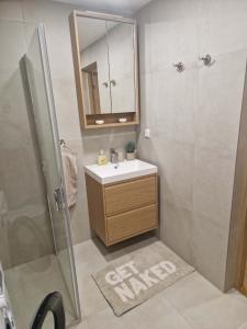a bathroom with a sink and a shower with a mirror at Oja 69-4 Apartment in Pärnu