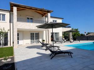 a patio with chairs and an umbrella next to a pool at Villa Gaudeo with pool and EV station in Nova Vas