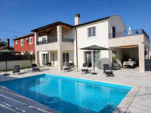 a villa with a swimming pool in front of a house at Villa Gaudeo with pool and EV station in Nova Vas