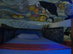 a bed in a room with a painting on the ceiling at Peacock Hostel in Ko Lanta