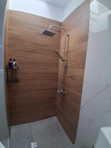a shower with a wooden wall in a bathroom at Elegance Apartments Mesologgi in Missolonghi