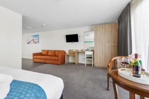 a hotel room with a bed and a couch and a table at Rainbow Motel Queanbeyan in Queanbeyan