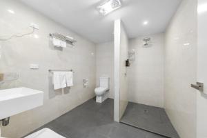 a white bathroom with a sink and a toilet at Rainbow Motel Queanbeyan in Queanbeyan +41 photos