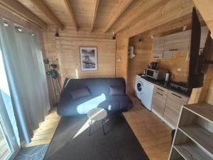 a small room with a blue couch and a kitchen at Le Ptit Châlet de Monnet in Monnet-la-Ville
