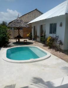 a swimming pool in front of a house with an umbrella at Uroa House in Uroa