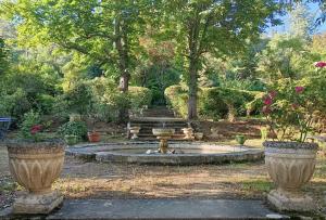 a fountain in a garden with two large vases at Maison Vive La Vie in Couiza
