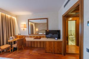 a hotel room with a television and a bedroom at Perugia Plaza Hotel in Perugia