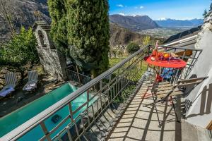 a balcony with a table and chairs next to a swimming pool at Mille Colline la Casa 1 with Shared Pool - Happy Rentals in Pianezzo +26 photos