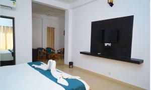 a bedroom with a bed and a tv on a wall at Blue River Resort in Rāmnagar