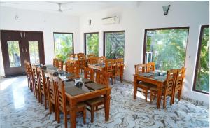 a dining room with wooden tables and chairs and windows at Blue River Resort in Rāmnagar