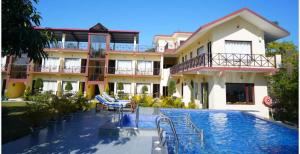a hotel with a swimming pool in front of a building at Blue River Resort in Rāmnagar