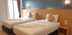 ein Hotelzimmer mit zwei Betten mit weißer Bettwäsche in der Unterkunft Ceniq Hotel in Sathani Nakhon Lampang