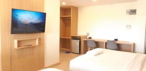 ein Zimmer mit einem Bett und einem Fernseher an der Wand in der Unterkunft Ceniq Hotel in Sathani Nakhon Lampang