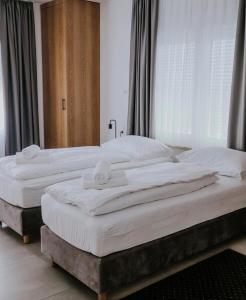 two beds in a bedroom with white sheets at Lovačka kuća Mandičevac in Mandičevac