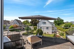 a patio with a table and an umbrella on a balcony at Das BRIX I Apartments zwischen See & Wald in Immenstaad in Immenstaad am Bodensee