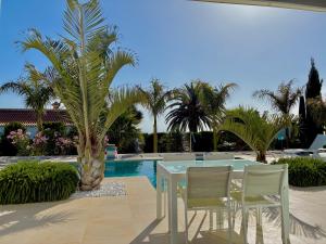 a table and chairs and a palm tree next to a pool at Casa Tajuya in Los Llanos de Aridane