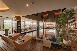 a large lobby with a pool with chairs and trees at Azana Boutique Hotel Solo in Purwosari