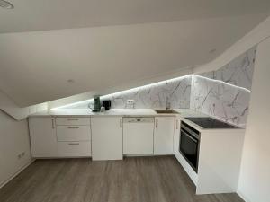 a white kitchen with white cabinets and marble walls at Čaršija Light Visoko in Visoko