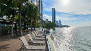 a row of chairs on a beach next to the water at Hompton Hotel by the Beach in George Town