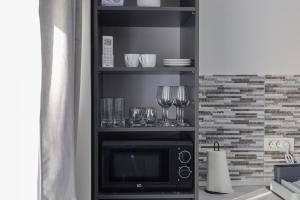 a kitchen with a microwave and wine glasses on a shelf at Kasa KEK - MCMXXV in Mangalia