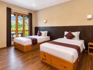 a bedroom with two beds and a window at hotel pema kara in Paro