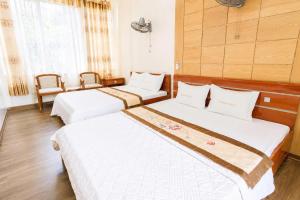 three beds in a room with wooden floors and windows at King Hotel Sầm Sơn in Sầm Sơn