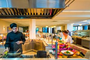 a man in a kitchen preparing food in a kitchen at Lagomandra Hotel and Spa in Lagomandra