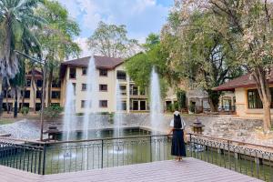 a woman standing on a bridge in front of a fountain at Pung-Waan Resort & Spa in Kanchanaburi City