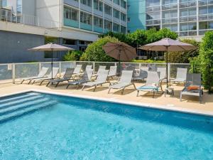 a group of chairs and umbrellas next to a pool at Mercure Cavaillon in Cavaillon
