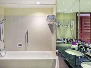 a bathroom with a large tub and two sinks at Mercure Jakarta Kota in Jakarta