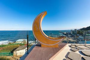 a large clock on a sidewalk next to the ocean at Donghae 828 Spa Pension A in Donghae +24 photos