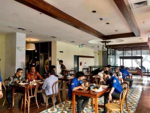 a group of people sitting at tables in a restaurant at StarRay Hotel Jakarta Kebayoran in Jakarta