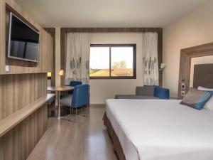 a hotel room with a bed and a table and a window at Novotel Campo Grande in Campo Grande +75 photos