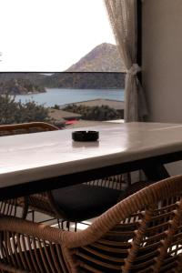a table with chairs and a window with a view at Alkida Luxury Rooms Tolo in Tolo +58 photos