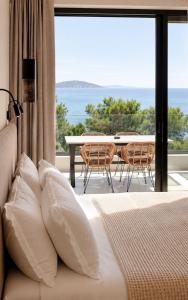 a bedroom with a bed and a balcony with a table at Alkida Luxury Rooms Tolo in Tolo
