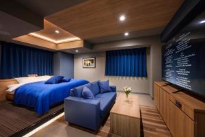 a bedroom with a blue bed and a tv at Hotel FLOW in Misato